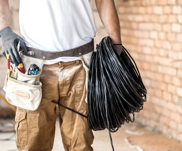 Electrician with tools, working on a construction site. Repair and handyman concept. House and house reconstruction.